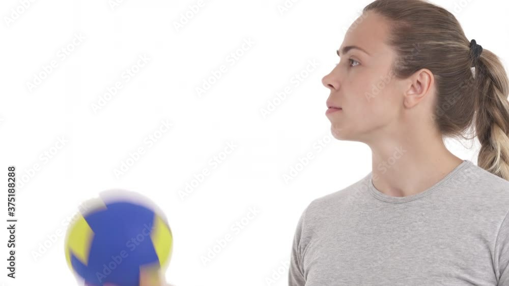 Young Caucasian sportswoman bouncing handball ball in air. Throwing drills. Tilting camera. Isolated on white background Young Caucasian sportswoman bouncing handball ball in air. Throwing drills. Tilting camera. Isolated on white background