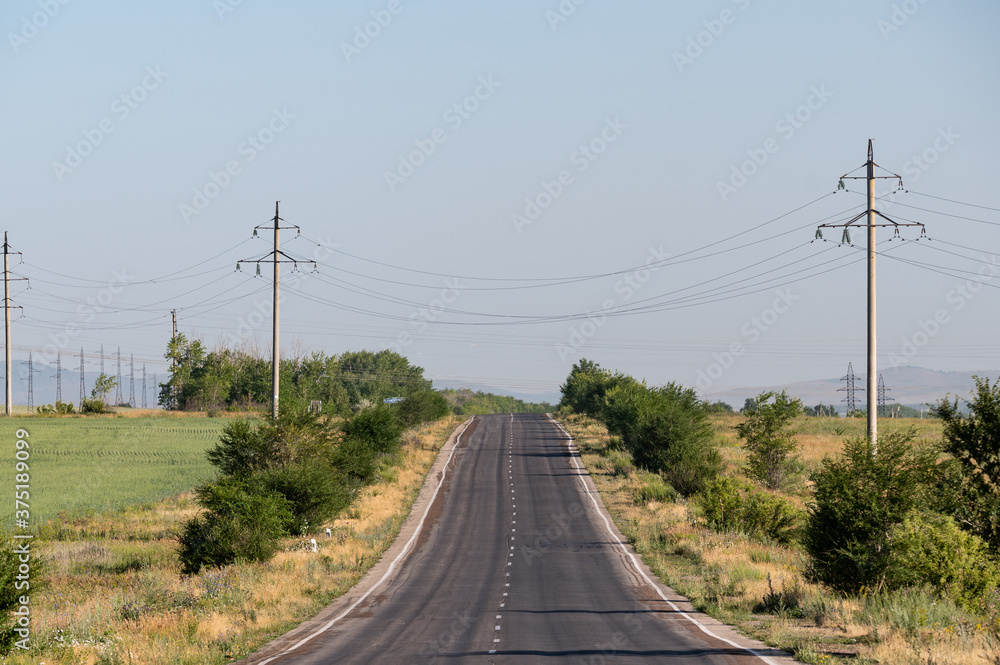 Rough asphalt road with power lines