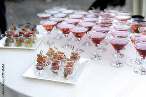 Set of cold snacks, jamon as the main snack. In the background drinks in beautiful glasses.