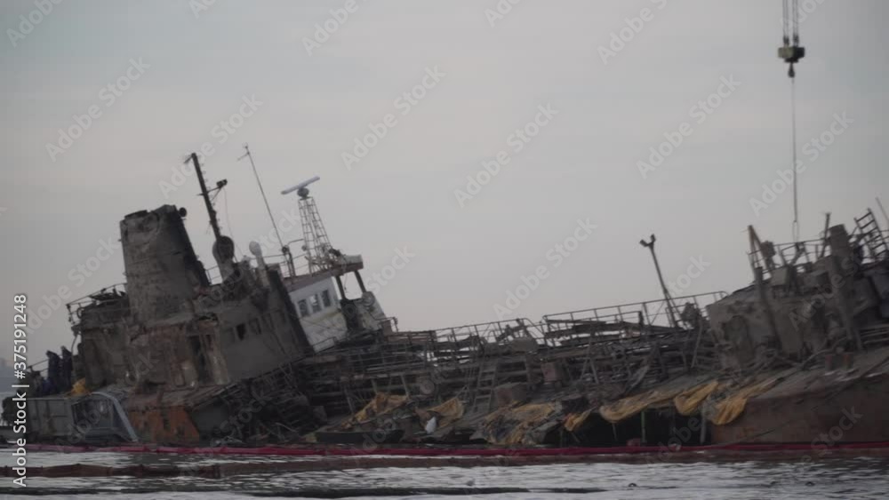 Rescue and recovery wrecked oil tanker Delfi in Odessa, Ukraine near Black Sea coast. Marine Crane lifts wreck Delphi into sea. Old rusty ship lies on side aground, tug pulls ship out after accident Rescue and recovery wrecked oil tanker Delfi in Odessa, Ukraine near Black Sea coast. Marine Crane lifts wreck Delphi into sea. Old rusty ship lies on side aground, tug pulls ship out after accident