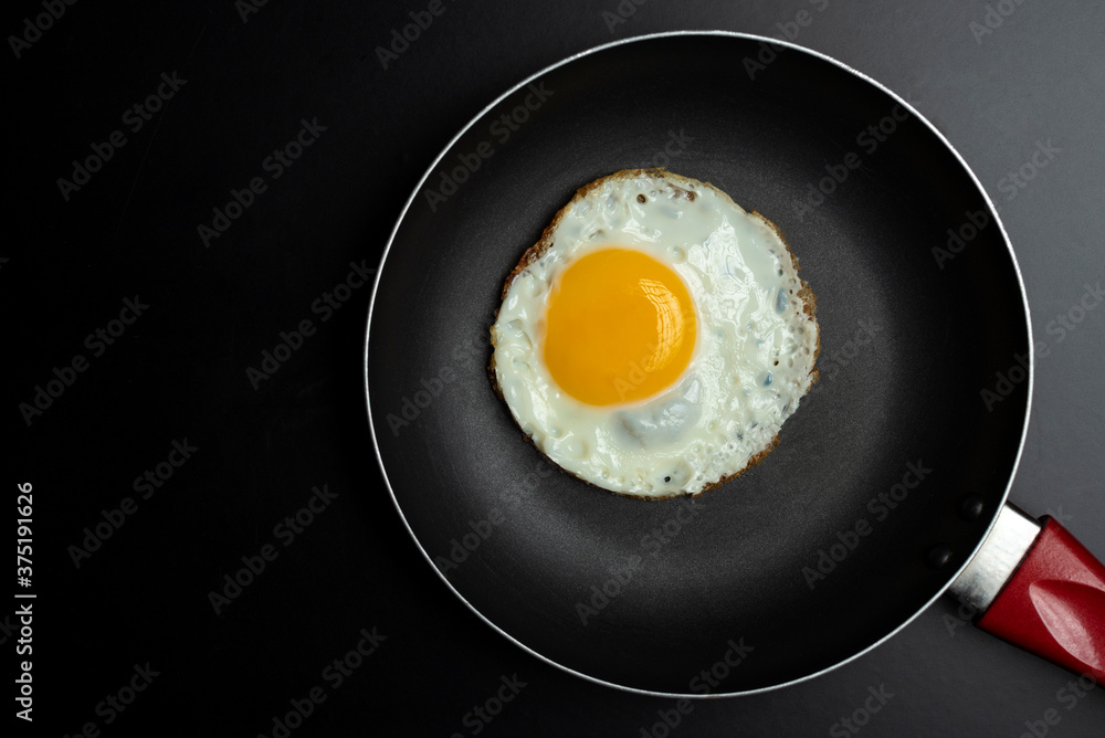 fried egg in black pan and parsley, on black background fried egg in black pan and parsley, on black background