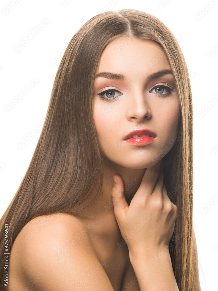 Fototapeta premium Young attractive female model with professional makeup looking at camera and touching face isolated on white.
