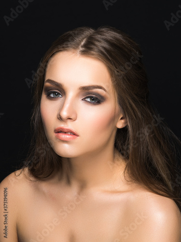 Young pretty female model with sophisticated makeup looking at camera isolated on black.