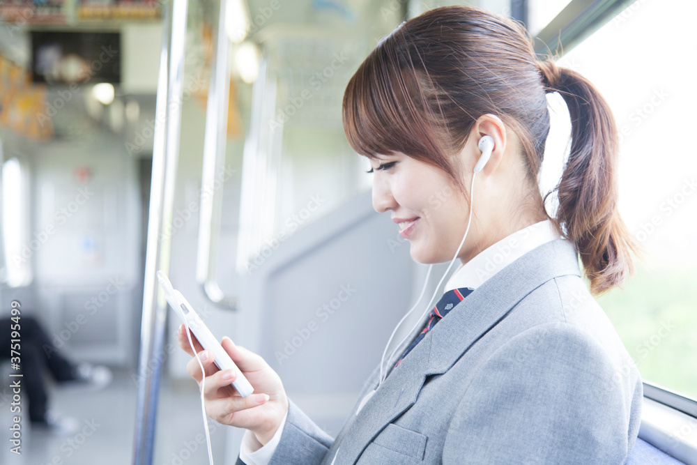 電車で音楽を聴く女子高校生 電車で音楽を聴く女子高校生