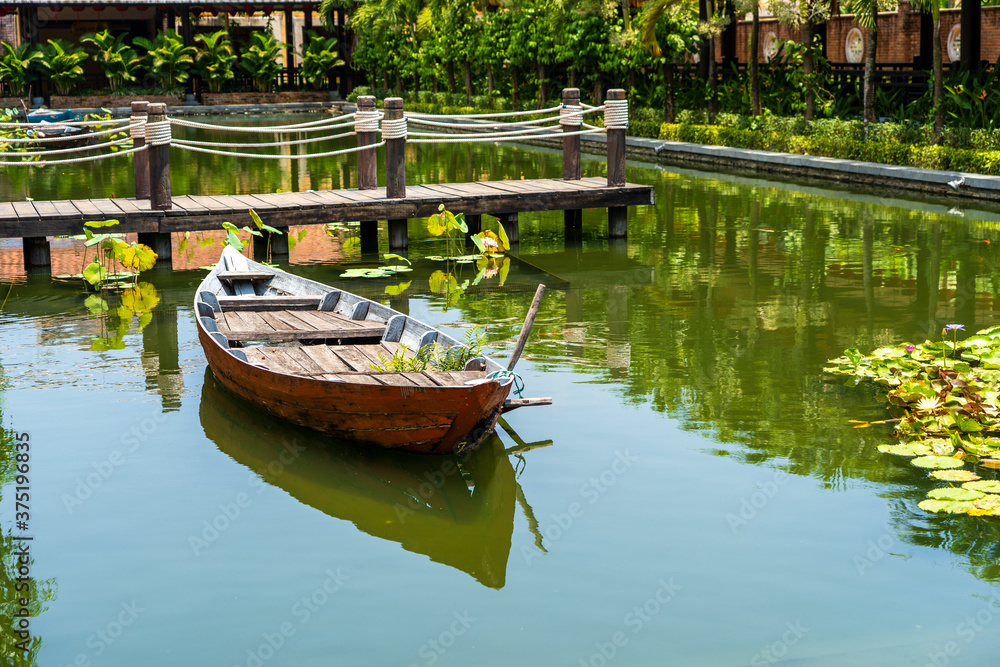 Wooden boat on the pond near the pier in a tropical garden in Danang, Vietnam