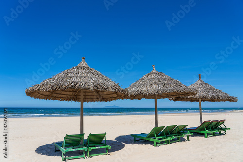 Tropical sand beach and summer sea water with blue sky and straw umbrella. Travel and nature concept