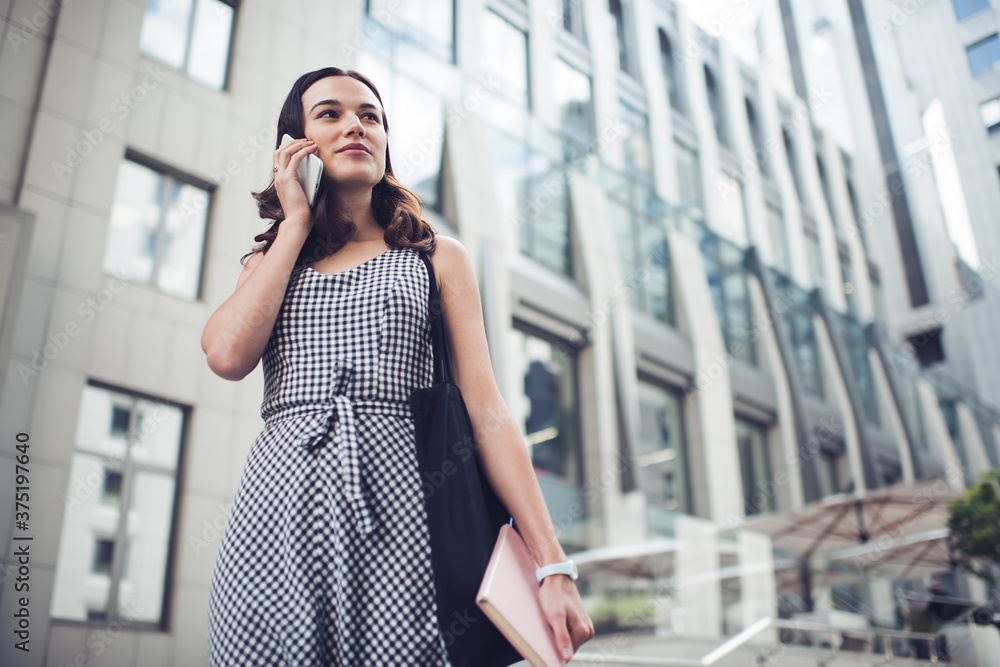 Calm adult confident business lady looking away while talking on phone on street Calm adult confident business lady looking away while talking on phone on street