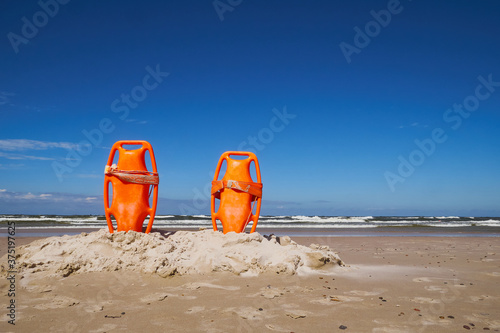 Closeup of some colorful rescue buoys in the sand of a beach in the Baltic sea.