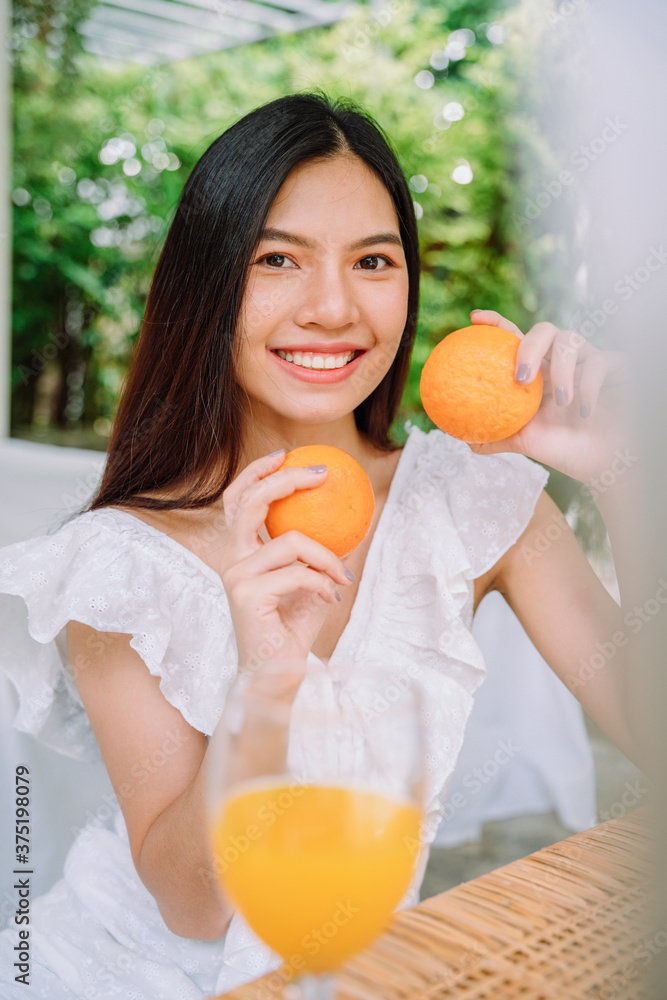 Beautiful asian thai woman long dark hair in white shirt enjoy drinking healthy orange juice.
