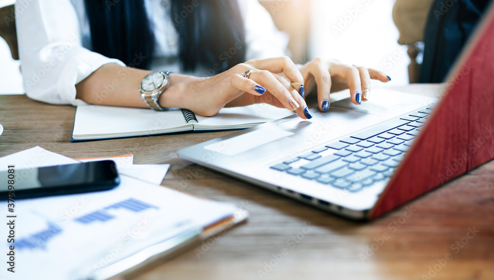 Close up and motion blurred of hand young businesswoman typing on laptop keyboard while she working with paperwork of investment on desk Close up and motion blurred of hand young businesswoman typing on laptop keyboard while she working with paperwork of investment on desk