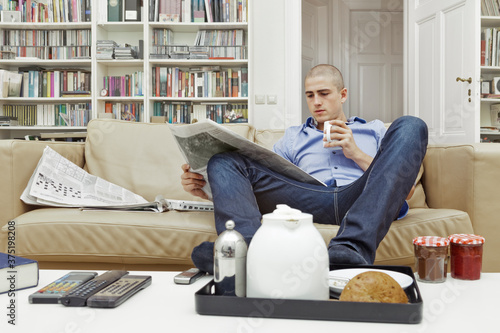 Young Man's Breakfast in Living Room While Reading Newspaper