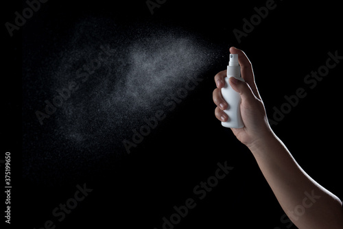 Hand spraying antiseptic against virus isolated on black background