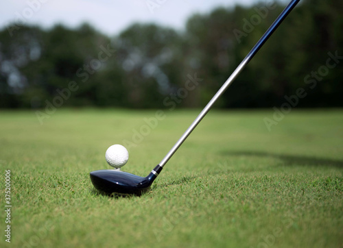 Golfer sets club in front of golf ball on tee