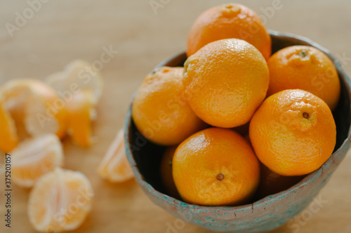 Tangelos in a bowl with an open tangelo on the table