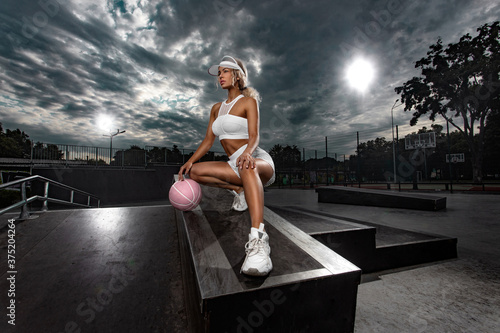 Beautiful and sexy fit woman in outfit with a basketball ball. Sport and sportswear fashion concept