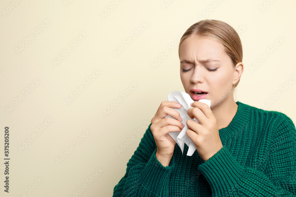 Young woman sneezing on light background, space for text. Cold symptoms Young woman sneezing on light background, space for text. Cold symptoms
