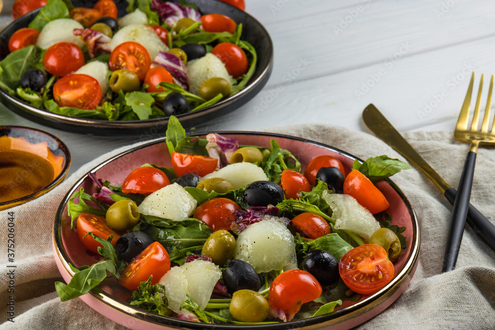 Two servings of salad with melon, tomatoes and olives