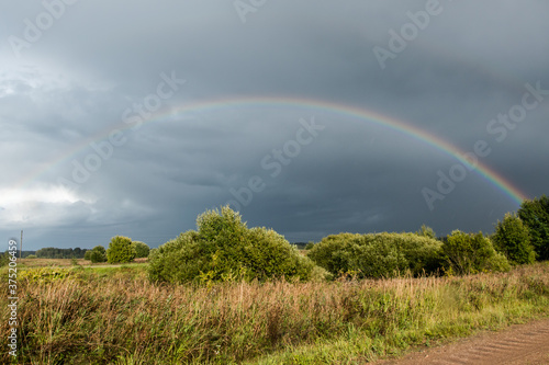Landscape. Weather specific. Colorful rainbow in dramatic sky after the rain.