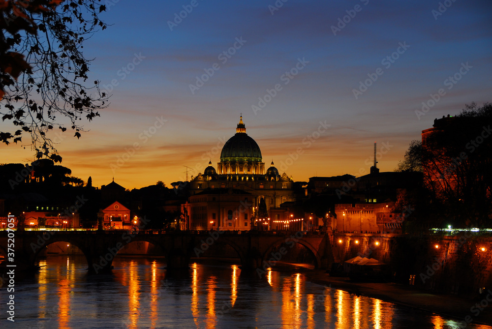 Beautiful sunset view of Rome along River Tiber with the iconic St Peter illuminated