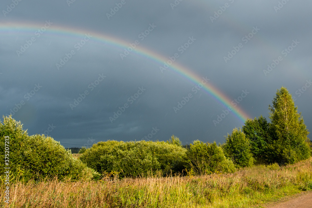 Landscape. Weather specific. Double colorful rainbow in dramatic sky after the rain. Landscape. Weather specific. Double colorful rainbow in dramatic sky after the rain.