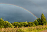Landscape. Weather specific. Double colorful rainbow in dramatic sky after the rain.