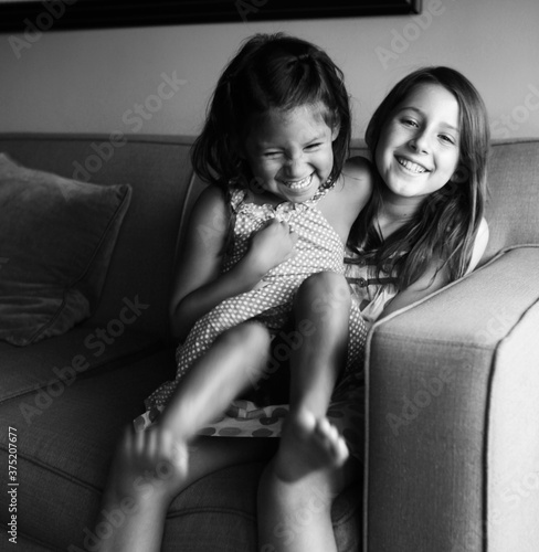 Two multiethnic girls giggling on couch in black and white photo