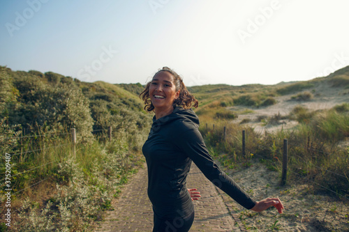 Young woman tunes around during her workout in the dunes photo