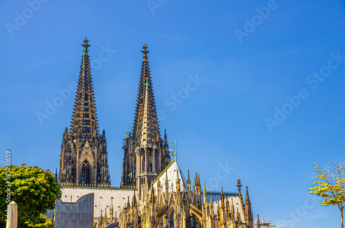 Two huge spires of Cologne Cathedral Roman Catholic Church Saint Peter gothic architectural style building in historical city centre, blue sky in sunny day copy space, North Rhine-Westphalia, Germany