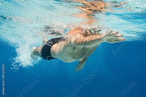 Pro male swimmer in the blue water