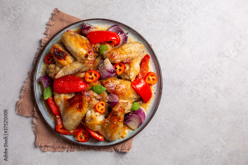 Baked chicken wings marinated in orange jam, with bell peppers, hot peppers and red onions.
