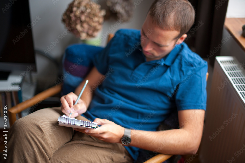 seated man writing in a notepad seated man writing in a notepad