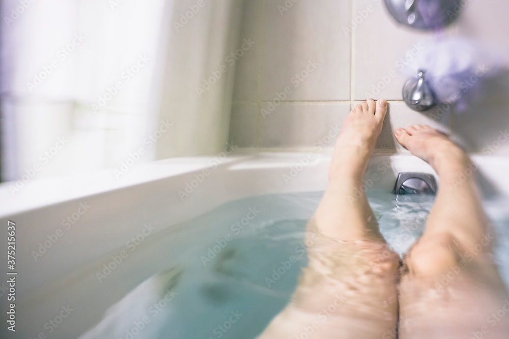 © Holly Clark/Stocksy - A woman's legs and feet in a bathtub.