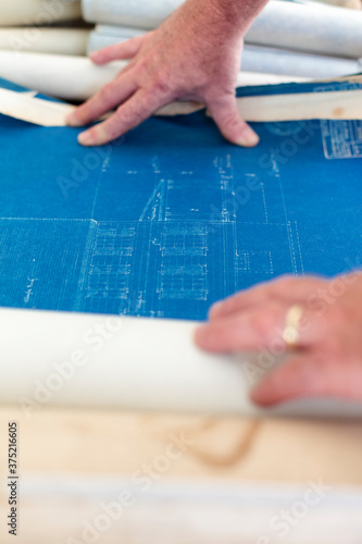 A man's hands spread out an antique architectural drawing. archi photo