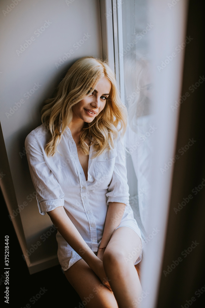 Young blond woman sitting by window at day light Young blond woman sitting by window at day light