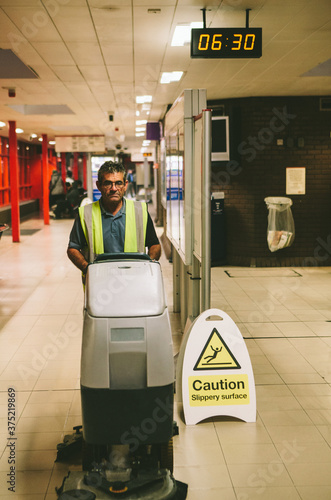 Worker cleaning floor with a scrubber dryer. photo