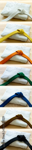 Martial arts colored belts and uniforms on a wood background.