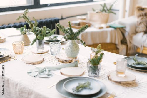 Blue plates, gold Cutlery, a spruce branch on a plate, pine branches in vases. Festive Christmas winter dinner or family dinner service