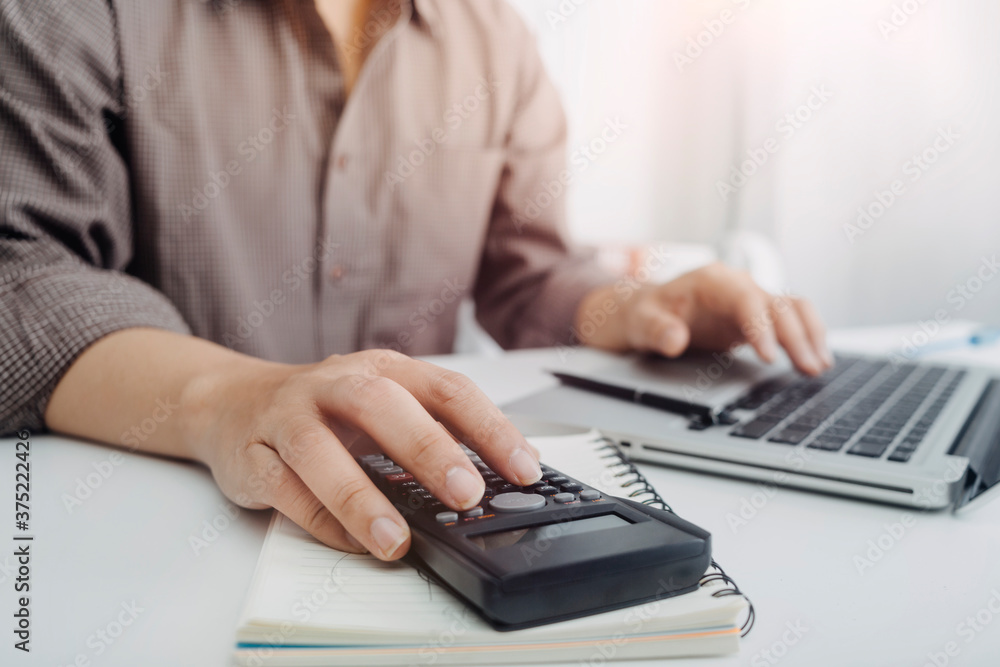 Businesswomen hands working with finances about cost and calculator and laptop with tablet, smartphone at office in morning light Businesswomen hands working with finances about cost and calculator and laptop with tablet, smartphone at office in morning light