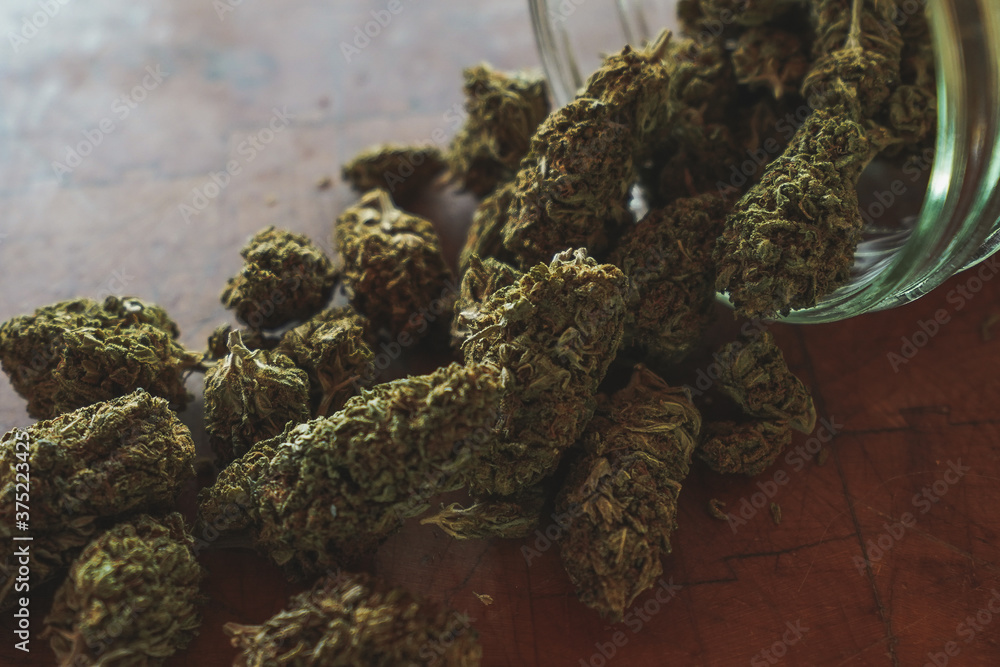 Fototapeta premium Dried Cannabis with jar and wood background 
