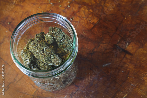 Dried Cannabis with jar and wood background   photo