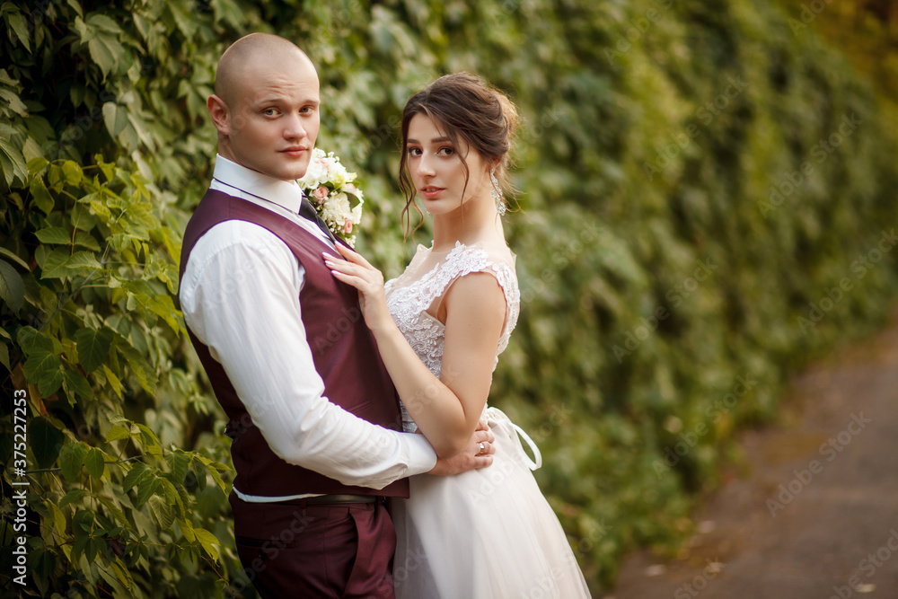 Romantic couple newlyweds, bride and groom stands and holding bouquet of flowers and greens, greenery in the Botanical green garden. Wedding ceremony on nature.