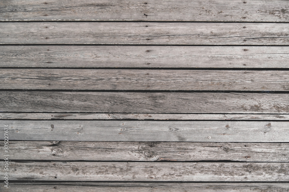 Old unpainted wooden planks as horizontal background, wooden floor with cracks and nails Old unpainted wooden planks as horizontal background, wooden floor with cracks and nails
