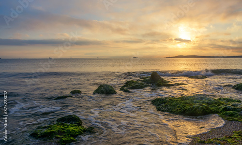 Foaming wave  breaking at sunrise with a rocky shoreline