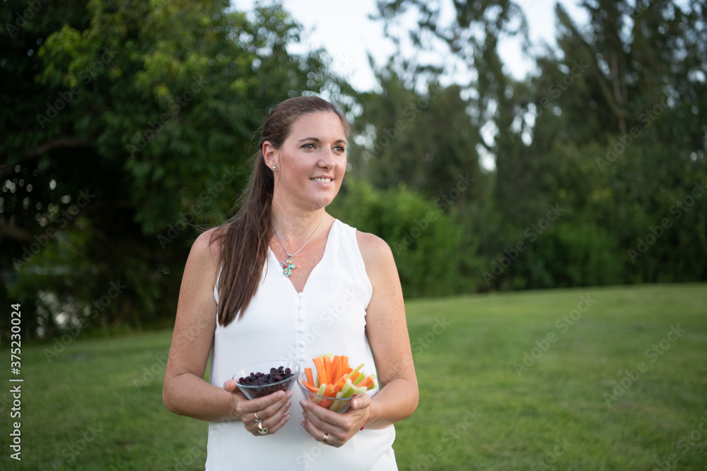 woman holding two healthy snacks outdoors