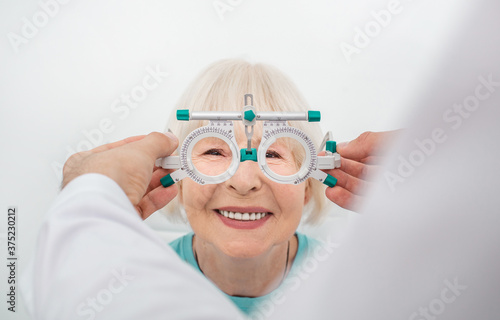 Senior woman wearing optometrist trial frame at ophthalmology clinic. Selection of diopter glasses for treatment of a woman vision
