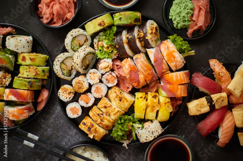 Asian food fest. Menu sushi with nigiri, maki, uramaki on black plates. Various kinds of sushi