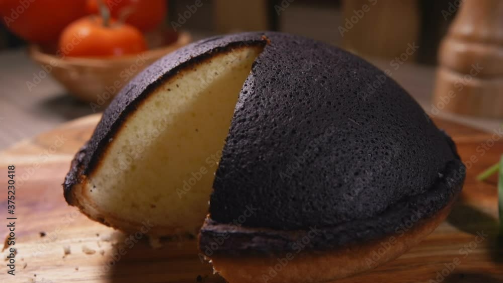 Hand takes a piece of Tourteaux Jahan black cottage cheese pie with a knife from a wooden board on the background of tomatoes Hand takes a piece of Tourteaux Jahan black cottage cheese pie with a knife from a wooden board on the background of tomatoes