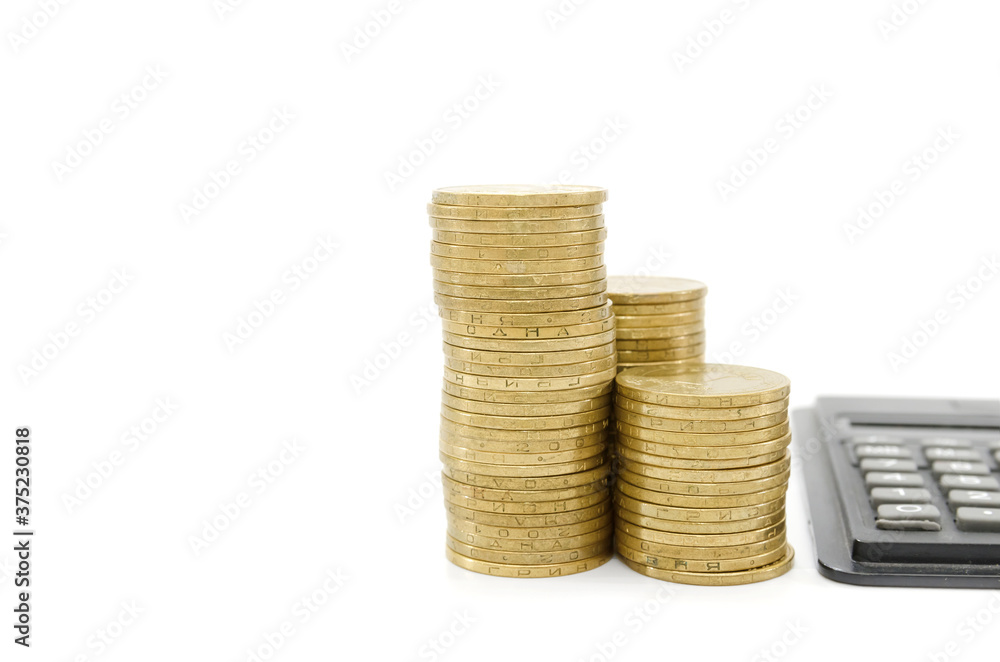 stacks of gold coins of different heights and a calculator isolated on white background. Copy of space. Place for text