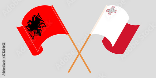 Crossed and waving flags of Albania and Malta