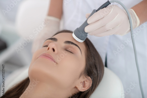 Cosmetologist making laser face smoothing to the customer